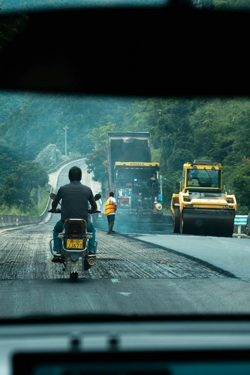 A construction site with autonomous Caterpillar machinery working seamlessly with human overseers in a coordinated effort