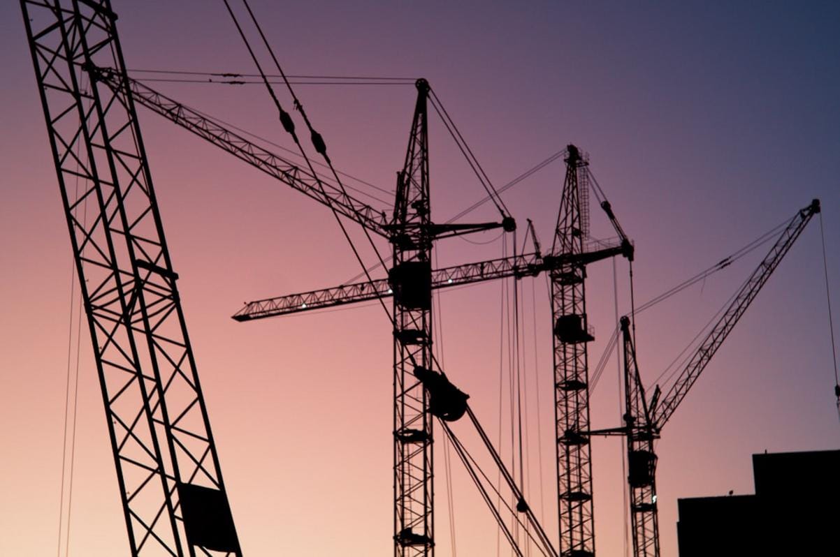 A modern construction site with excavators, cranes, and bulldozers actively working together at dawn.