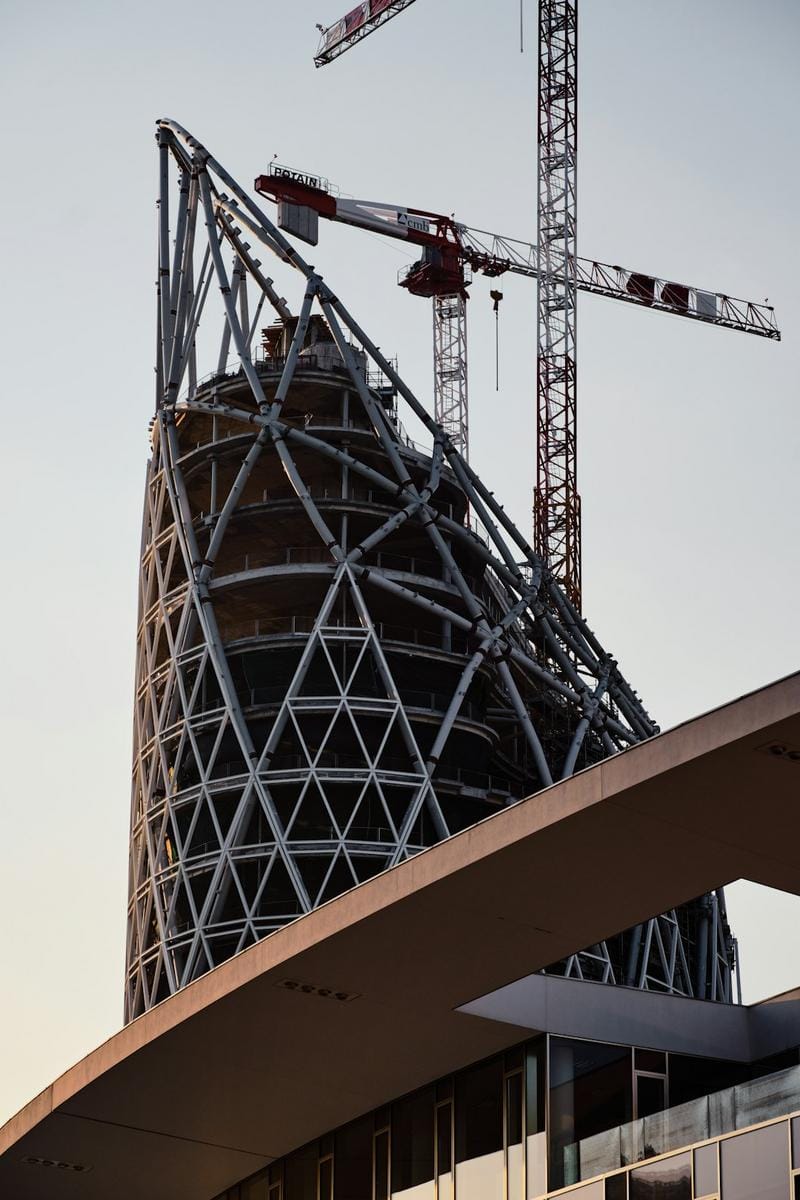 Futuristic construction site with robotic machinery and eco-friendly ready-mix plant in operation amidst a city skyline.