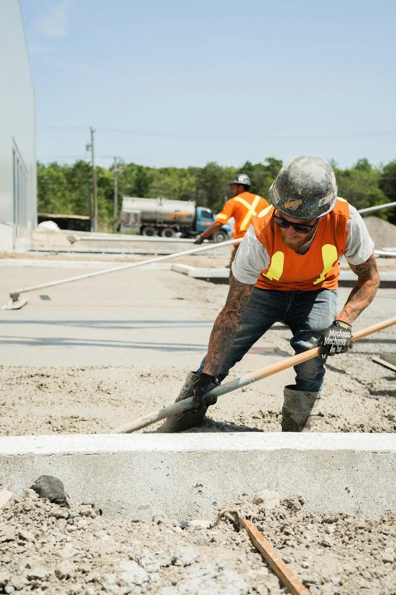 Construction workers operating an automated ready-mix concrete batching plant on a commercial building site.